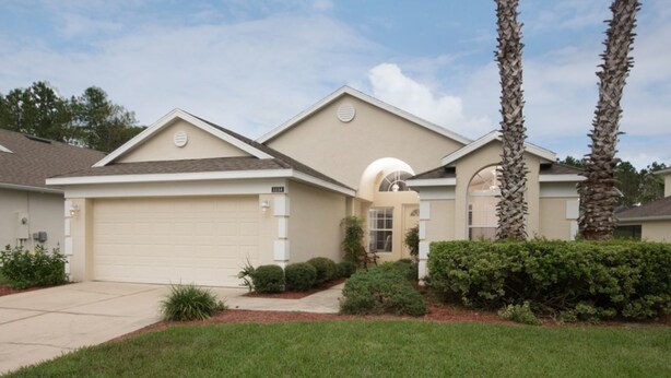 A single-story house with a beige exterior, a garage, and a well-maintained lawn. - Highlands Reserve Golf & Country Club 1114 (Davenport)