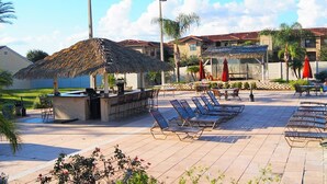 A poolside area with lounge chairs, a bar, and umbrellas. - Regal Palms Resort & Spa 1215 (Davenport)