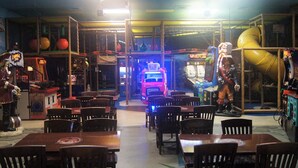 A restaurant with booths and tables, arcade games, and a neon-lit pink vehicle in the background. - Regal Palms Resort & Spa 1215 (Davenport)