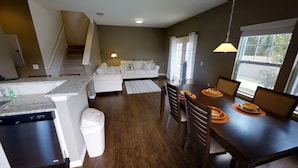 A modern kitchen with a dishwasher, a dining table with chairs, a sofa, and a staircase. - West Lucaya 8996 (Kissimmee)