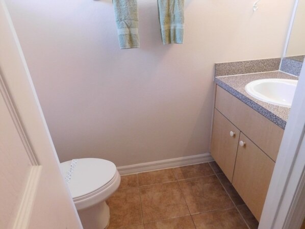A small bathroom with a toilet, a sink, and a towel hanging on the wall.