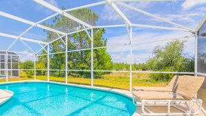 A covered swimming pool with a lounge chair and a pergola structure.