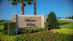 A sign for Windsor Palms, a green resort community, with a landscaped garden and palm trees.