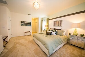 A bedroom with a large bed, a nightstand, a dresser, a chandelier, and a painting on the wall. - Solterra 4043 (Davenport)