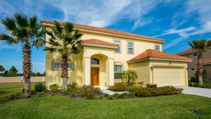 A two-story house with a red-tiled roof, a yellow facade, and a front yard with palm trees and shrubs. - Solterra 4043 (Davenport)