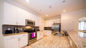 A modern kitchen with white cabinets, granite countertops, stainless steel appliances, and a built-in oven. - Solterra 4043 (Davenport)