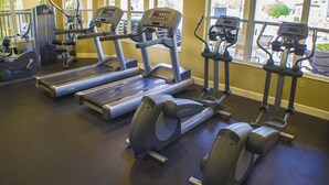 A gym with various exercise equipment including treadmills, elliptical machines, and stationary bikes.