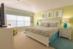 A bedroom with a bed, bedside tables, a desk, and a window with blinds. - Windsor Hills 2540 (Kissimmee)