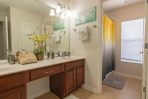 A bathroom with a double sink vanity, a large mirror, and a shower curtain. - Windsor Hills 2540 (Kissimmee)