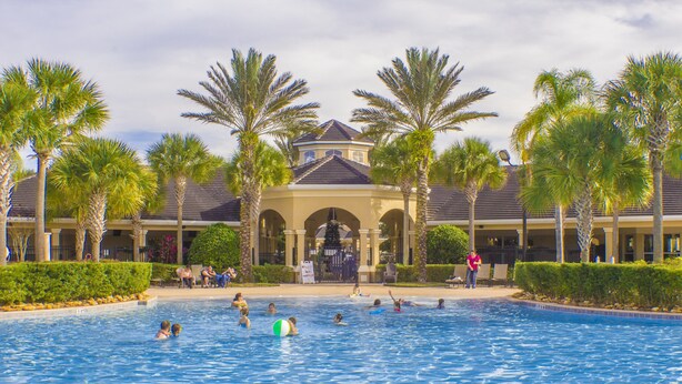 A swimming pool with palm trees and a building in the background.
