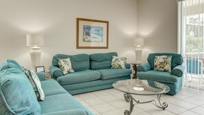 A living room with teal sofas, a glass coffee table, and two wall-mounted lamps. - Highlands Reserve Golf & Country Club 447 (Davenport)