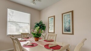 A dining room with a table set for four, surrounded by chairs, a potted plant, and two framed artworks on the wall. - Highlands Reserve Golf & Country Club 447 (Davenport)