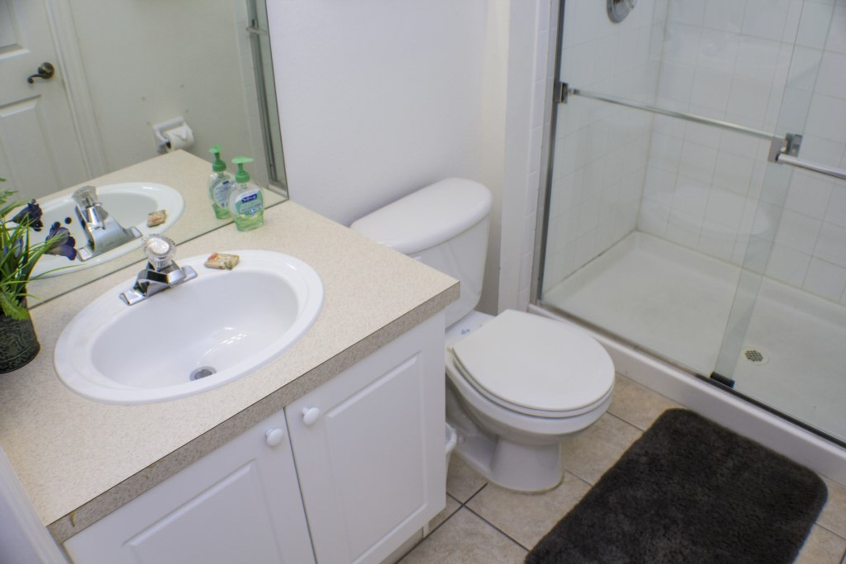 A bathroom with a sink, toilet, and glass shower enclosure.
