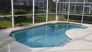 A swimming pool with a white deck, surrounded by a covered area with a metal frame and glass panels. - Highlands Reserve Golf & Country Club 1111 (Davenport)