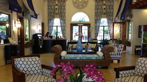 A lobby with a reception desk, patterned sofas, and a large vase with flowers. - Paradise Palms 8955 (Kissimmee)