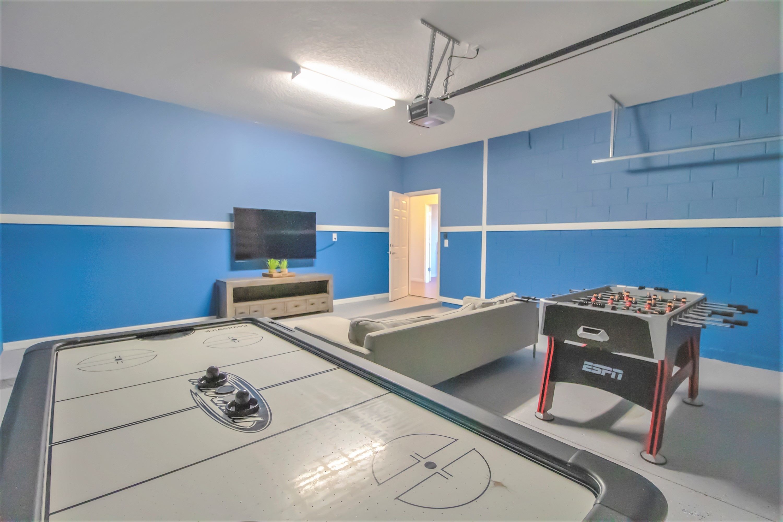 Una habitación con mesa de fútbol, televisor de pantalla plana y sofá.