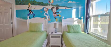 A room with two beds, a nightstand, and a mural of cartoon characters on the wall.