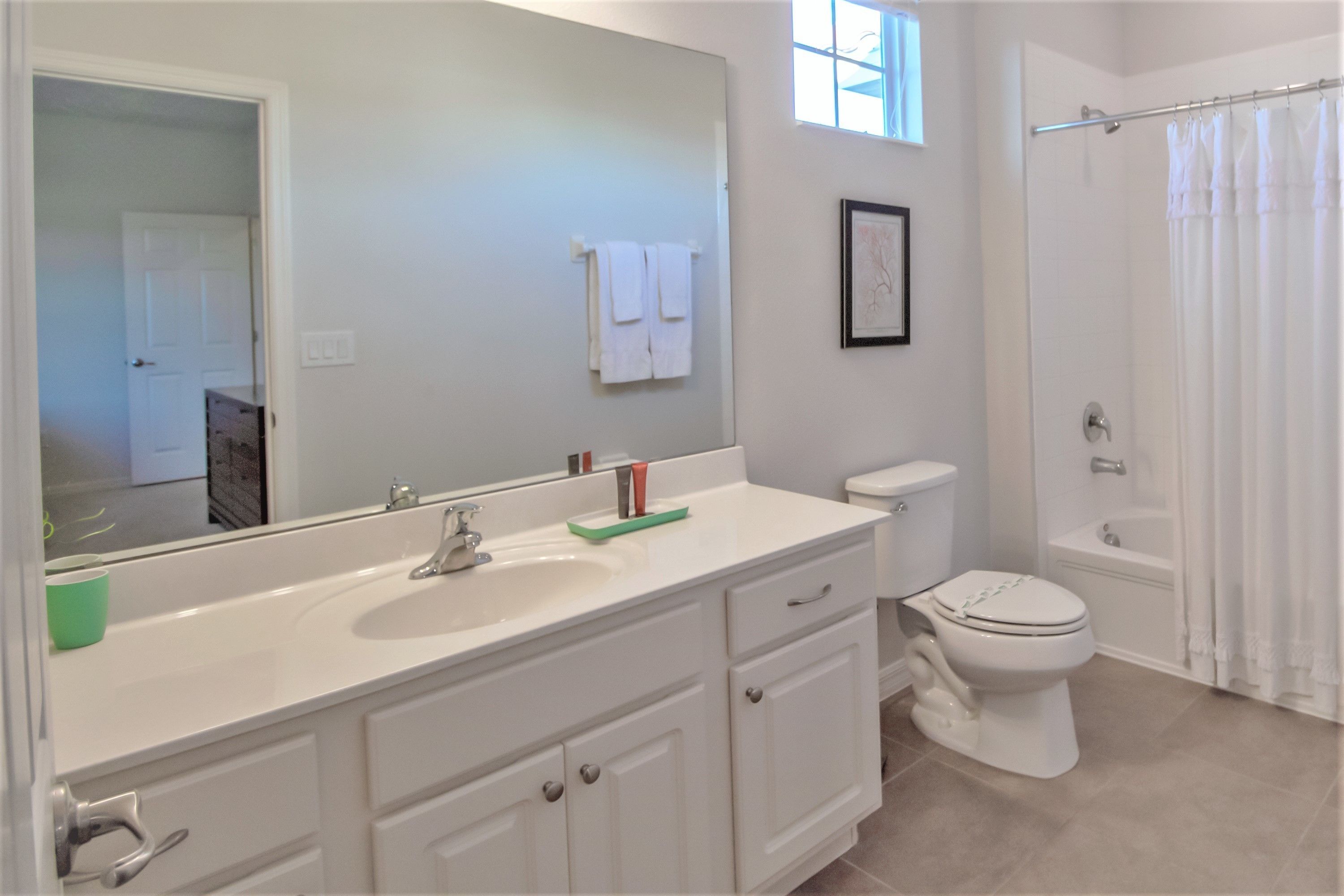 A bathroom with a white sink, mirror, toilet, and bathtub.