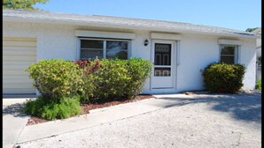 A single-story house with a front door, two windows, and a small front yard with bushes. - Bonita Springs 23 (Bonita Springs)