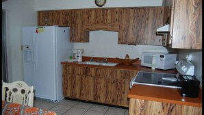A kitchen with wooden cabinets, a refrigerator, a microwave, a coffee maker, and a sink. - Bonita Springs 23 (Bonita Springs)