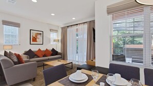 Una sala moderna con sofá, mesa de centro y comedor con mesa dispuesta para dos.