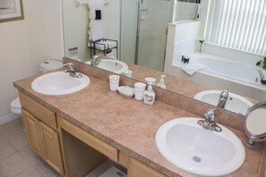 Une salle de bain avec deux lavabos, un grand miroir et un espace douche.