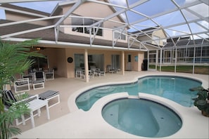 An indoor swimming pool with lounge chairs and a covered patio area.