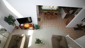 Een ruime woonkamer met een zithoek, een flatscreen-televisie en een eethoek met een tafel en stoelen.