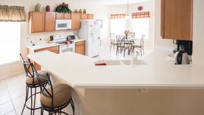 A modern kitchen with wooden cabinets, a white countertop, and a central island with bar stools.