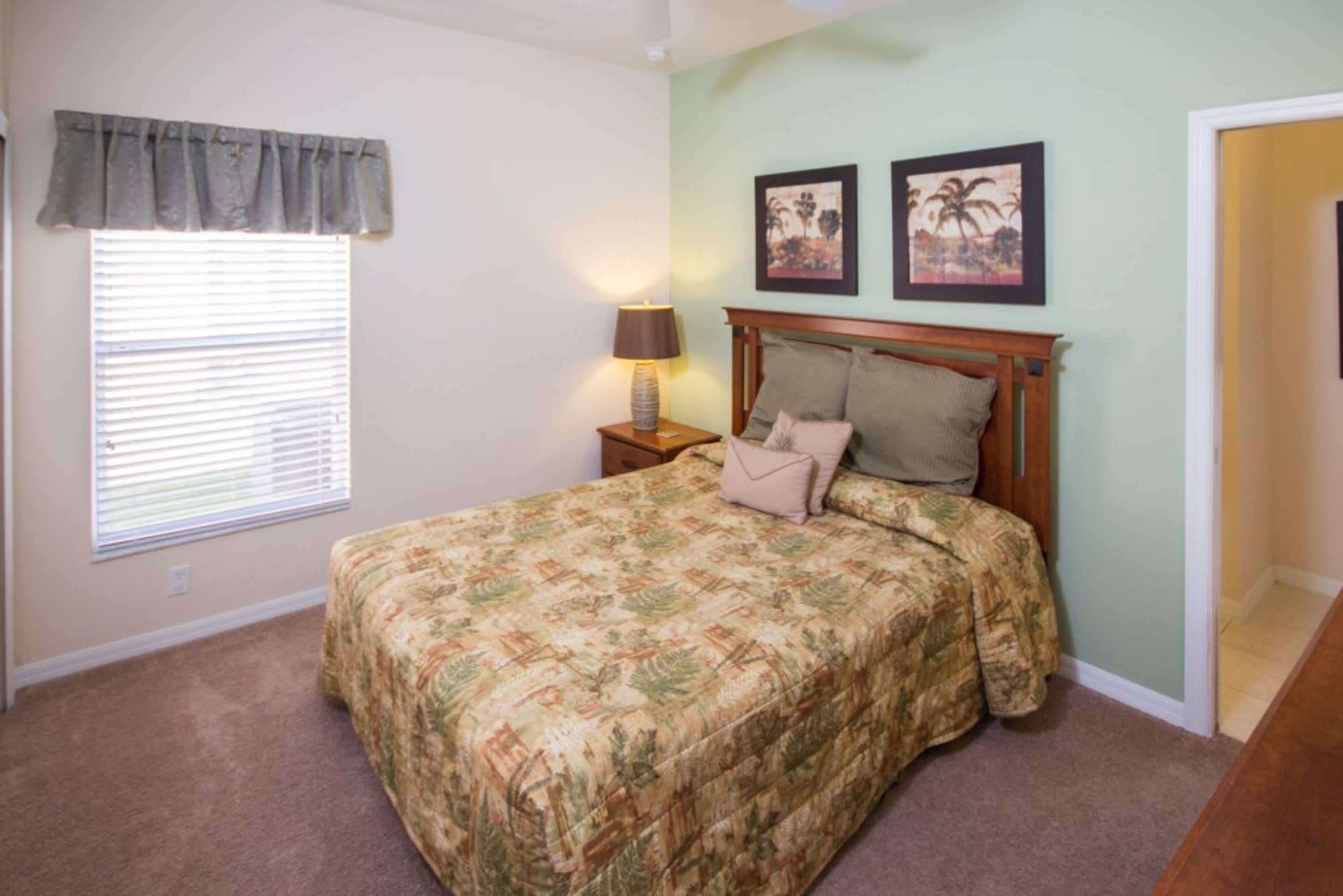 A bedroom with a bed, a nightstand, a lamp, and two framed pictures on the wall.
