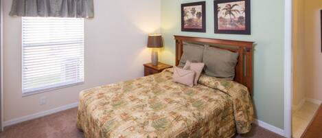A bedroom with a bed, a nightstand, a lamp, and two framed pictures on the wall.