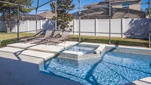 A swimming pool with a hot tub, surrounded by a covered patio with lounge chairs.