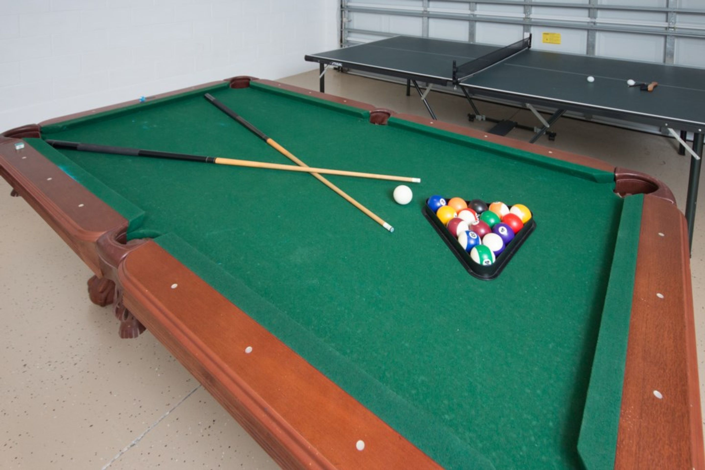 A pool table with a green felt surface, pool cues, and a set of balls.