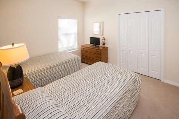 A bedroom with two beds, a dresser, a TV, and a closet.