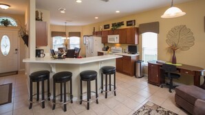 Una cocina moderna con una isla central, taburetes de bar, un microondas y un refrigerador.
