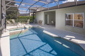 A swimming pool with a covered patio area, lounge chairs, and a view of the surrounding landscape. - The Shire at West Haven 823 (Davenport)