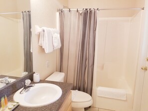A bathroom with a sink, toilet, and shower curtain.
