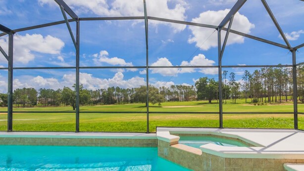A swimming pool with a view of a golf course through a covered area.