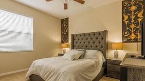 A bedroom with a tufted headboard, a bed with white bedding, two bedside tables with lamps, a nightstand, and a wooden desk.