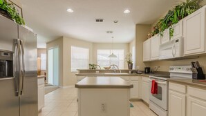 A modern kitchen with a central island, stainless steel appliances, and white cabinetry.