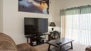 A living room with a flat-screen TV, a coffee table, a sofa, and a window with blinds. - Wellington 132 (Davenport)