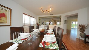 A dining room with a long wooden table set for a meal, flanked by chairs, with a ceiling light fixture above. - Four Corners 908 (Davenport)