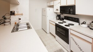 Une cuisine moderne avec des meubles blancs, un micro-ondes noir, une cuisinière et un évier.