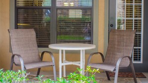 A patio area with two chairs and a small table, a door with a window, and a view of the outside. - Bella Piazza 906 - 414 (Davenport)