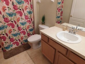 A bathroom with a toilet, a sink, and a mirror. - Coral Cay 2475 (Kissimmee)