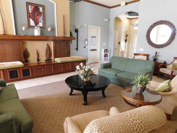 A living room with a green sofa, a leopard print armchair, a coffee table with a vase, and a wooden cabinet with decorative items. - Coral Cay 2475 (Kissimmee)