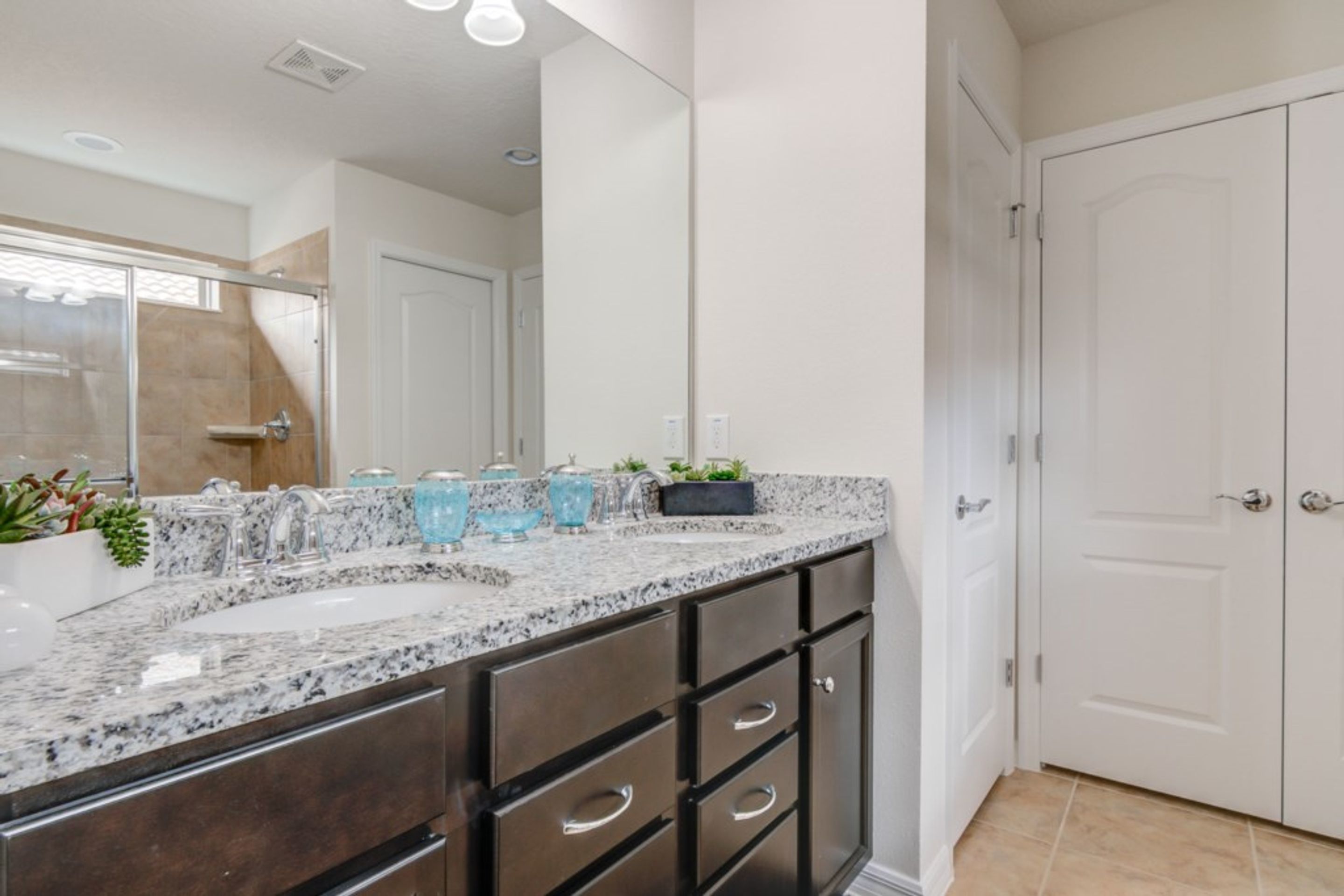 A bathroom with a double sink vanity, dark cabinets, and a large mirror.