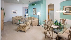 A living room with two sofas, a glass coffee table, and a dining table with chairs. - Highlands Reserve Golf & Country Club 349 (Davenport)