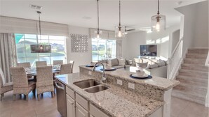 A modern kitchen with granite countertops, stainless steel appliances, and a dining area with wicker chairs. - Golden Palms Vacation Resort 2588 (Kissimmee)