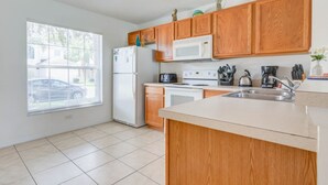 Une cuisine avec des meubles de rangement en bois, un réfrigérateur, un four à micro-ondes, une cuisinière et un évier.